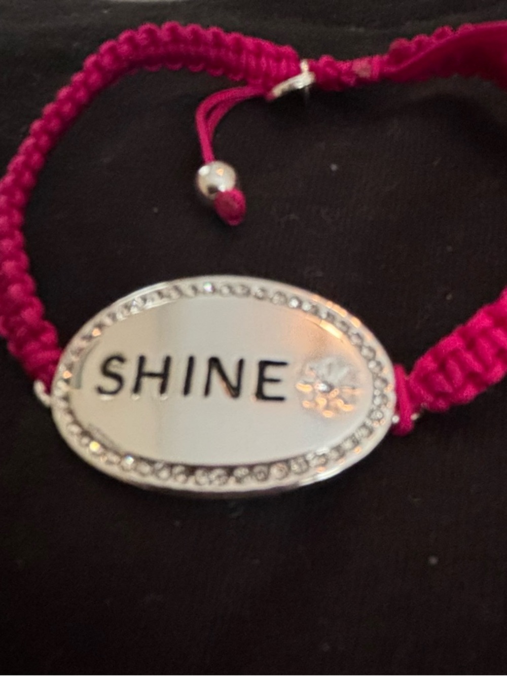 Fuchsia corded bracelet with silver bar that says Shine. Has crystal accents